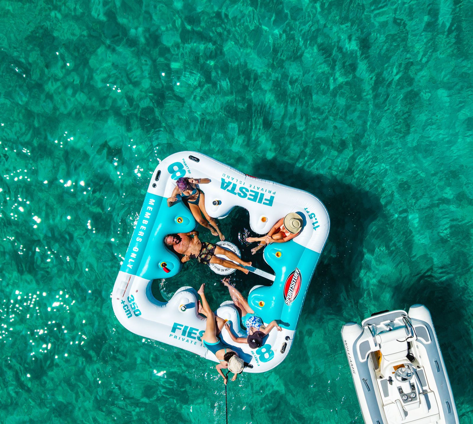 Guests on a giant float next to KayDee yacht aerial Bahamas